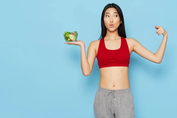 Mujer con un plato de ensalada figura delgada comida sana fondo azul —  Fotos de Stock