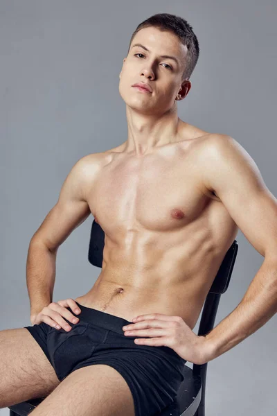 Handsome guy resting on a chair with a pumped-up body fitness gym — Stock Photo, Image