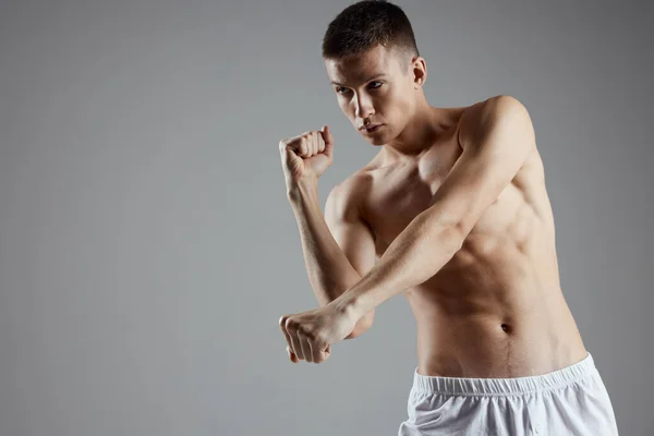 Boxer com músculos do braço bombeados em um fundo cinza e abs cubos em seu estômago — Fotografia de Stock