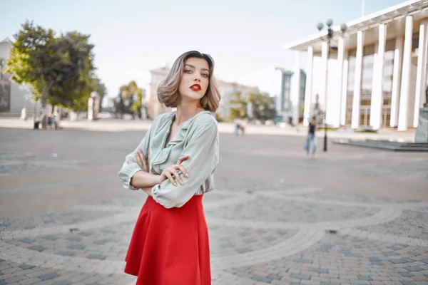 Glad kvinna i en röd kjol på torget i staden promenad — Stockfoto