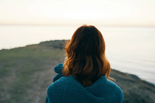Donna dai capelli rossi in montagna con un plaid blu sulle spalle vista posteriore — Foto Stock