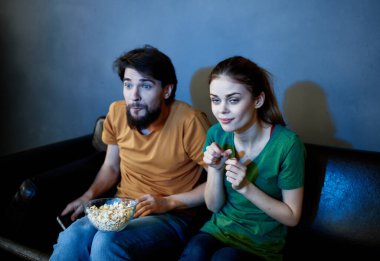 Karı koca kanepede kucaklaşıp televizyon izliyorlar.