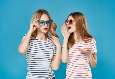 İki sevimli kız arkadaş yaz eğlencesi kucaklaşması mavi arka plan