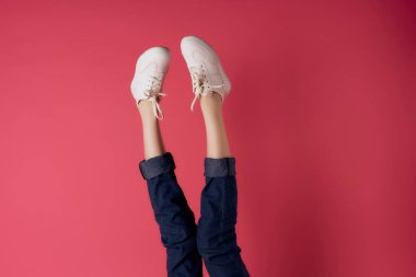 Beyaz spor ayakkabıları içinde ters dönmüş kadın bacakları.