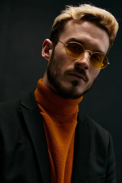 Stilvoller Mann mit Brille orangefarbener Pullover Mantel schwarzer Hintergrund — Stockfoto
