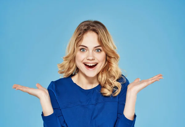 Überraschte emotionale Frau in blauem Kleid gestikulierend mit handblauem Hintergrund — Stockfoto