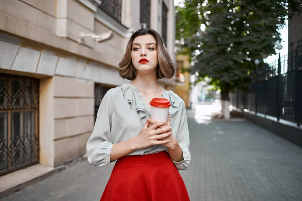 Vacker kvinna röd kjol kaffekopp utomhus promenad — Stockfoto