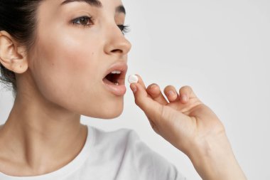 Elinde haplar olan beyaz tişörtlü kadın sağlık sorunları olan doktor.