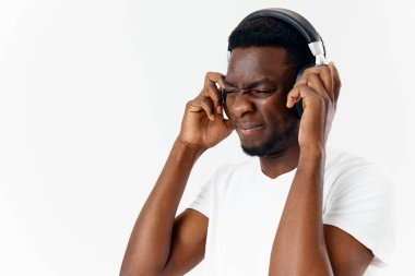 Kulaklıklı Afrikalı görünümlü bir adam kafasını yakın çekimde tutuyor.