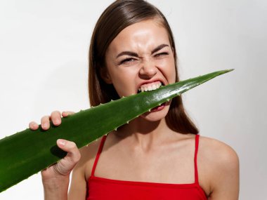 Gri arka planda kemiren çarşaflı kırmızı tişörtlü fevri bir kadın.