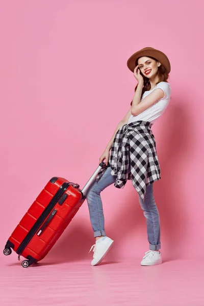 Веселая женщина с чемоданом багаж путешествия развлечения розовый фон — стоковое фото