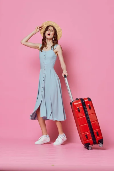 Женщина турист в шляпе с красным чемоданом пассажирский образ жизни розовый фон — стоковое фото