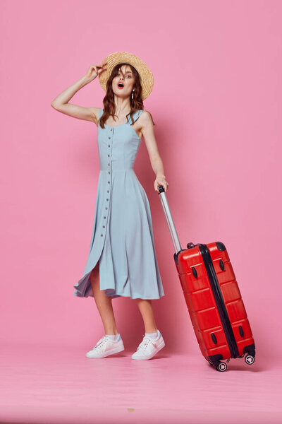 woman tourist in hat with red suitcase passenger lifestyle pink background