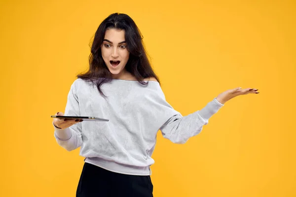 Morena com tablet em mãos emoções internet tecnologia amarelo fundo — Fotografia de Stock