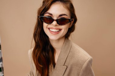 Bej ceketli çekici bir kadın. Güzel gülücük gözlüklü saç modeli.