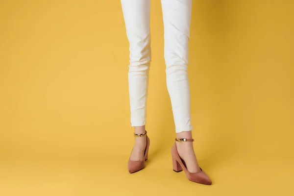 Pés femininos em posar sapatos moda temporada luxo fundo amarelo — Fotografia de Stock
