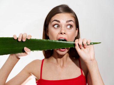 Açık arkaplanda aloe yaprağı ısıran aç bir kadın temiz cilt kozmetoloji modeli.