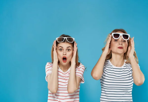 two women stand side by side in striped t-shirts fashion attractive look blue background