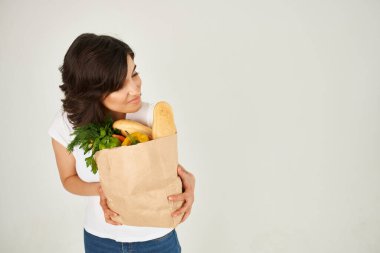 Beyaz tişörtlü tatlı esmer el çantası ve süpermarket alışverişi.