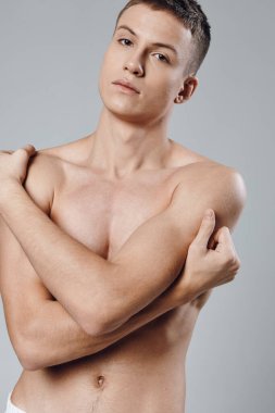 Karnında kasları şişmiş sporcu elleriyle kendine sarılıyor. 