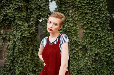 Kısa saçlı güzel bir kadın çalıların yanında kırmızı dudaklar