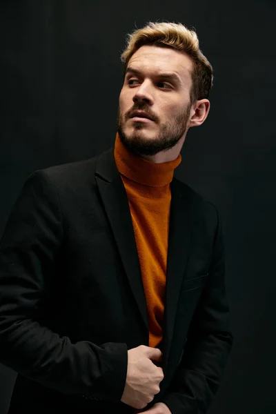 Modelo de hombre con estilo en un suéter naranja y chaqueta sostiene su mano en su cinturón — Foto de Stock