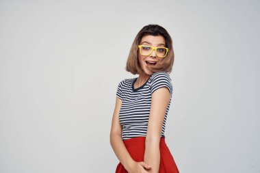 modern tarzda poz veren, gözlüklü, çizgili tişörtlü, neşeli, şık bir kadın.