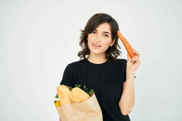 Mujer en una camiseta negra en un paquete con comestibles comida saludable entrega fondo claro —  Fotos de Stock