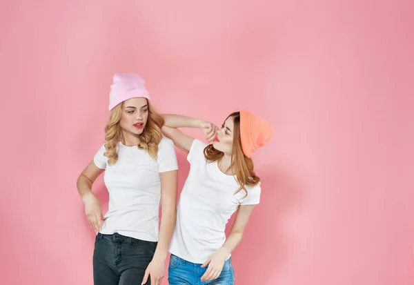 two women stand side by side youth style fun friendship pink background