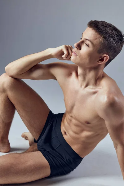 Jóképű férfi sportoló, felpumpált testtel a padlón ülve, közelről. — Stock Fotó