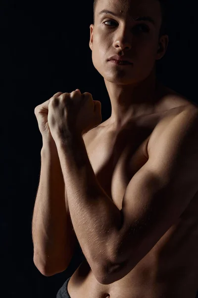 Sportovní chlap s čerpané paže svaly na černém pozadí při pohledu do strany zblízka — Stock fotografie