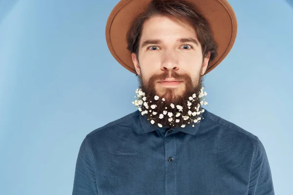 Hombre barbudo alegre en un sombrero y flores En su estilo de vida de pelo fondo azul —  Fotos de Stock