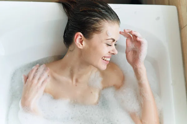 Mujer alegre se encuentra en el baño con espuma relajar la piel limpia —  Fotos de Stock