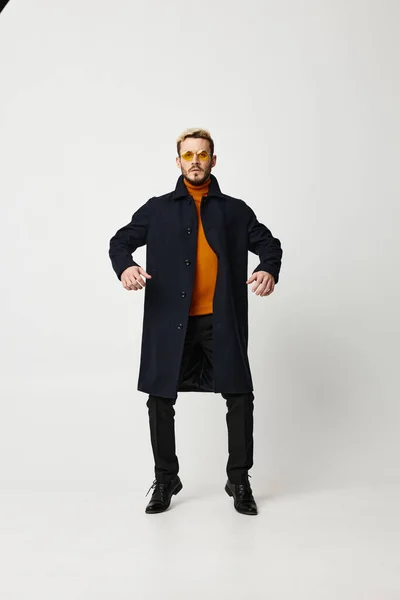 Модный мужчина в пальто держит руки на поясе и черные брюки модели светлый фон — стоковое фото