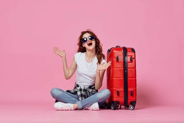 빨간 여행 가방 여권 과 비행기 표를 들고 핑크 색 배경 여행을 하는 명랑 한 여성 — 스톡 사진