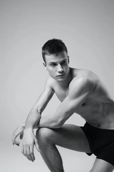 Atléta ül a földön beltéri rövidnadrágban és meztelen törzs fekete-fehér fotó fitness edzés — Stock Fotó