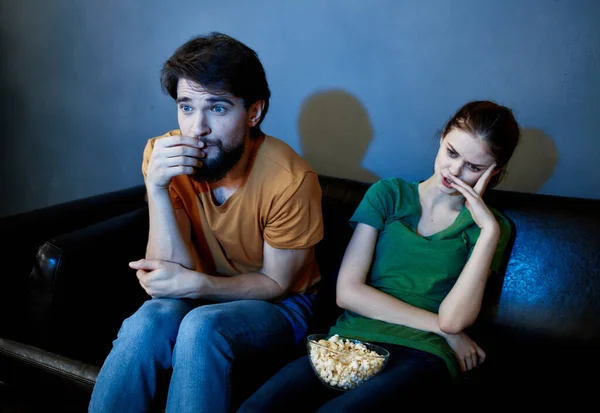 Junges Paar, das abends auf der Couch sitzt und Popcorn im Fernsehen guckt — Stockfoto