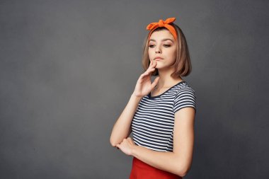 Sarışın, turuncu bantlı, çizgili tişörtlü koyu arkaplan pozu veren