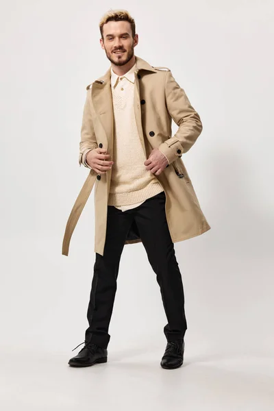 Tipo en un abrigo beige con un cinturón en la mano y pantalones negros modelo suéter — Foto de Stock