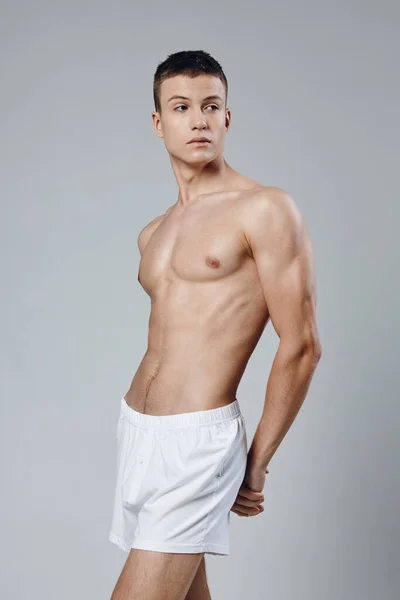 Macho con un atleta torso desnudo bombeado hasta los músculos del brazo y pantalones cortos blancos — Foto de Stock