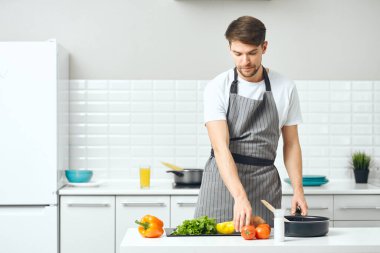 Mutfakta önlüklü bir adam yemek pişiriyor.