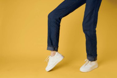 Kadın bacakları kırpılmış beyaz ayakkabılar modern stil sarı arka plan