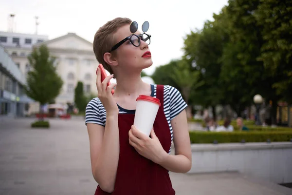 Mujer con un vaso de bebida en la calle caminar en gafas estilo de vida — Foto de Stock
