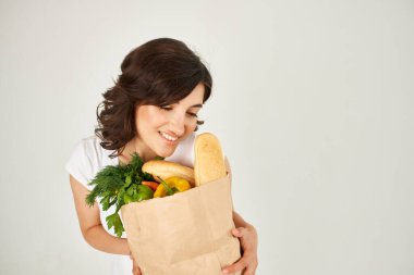 Beyaz tişörtlü tatlı esmer el çantası ve süpermarket alışverişi.
