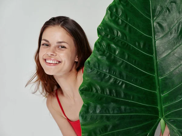 Mulher sorridente em maiô vermelho folha de palma charme luz fundo — Fotografia de Stock