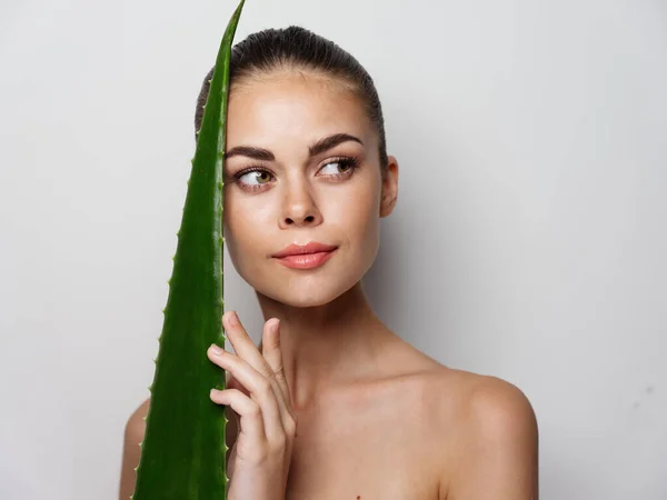 Mulher feliz com ombros nus segurando folha de aloé e sorrindo — Fotografia de Stock