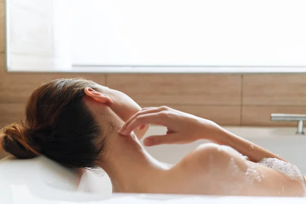 Woman with bare shoulders and lies in the bathroom with her back rest — Stock Photo, Image