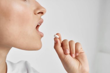 Kadın ağzına ilaç koyuyor. Sağlık ilaçlarını yakın plan çekiyor.