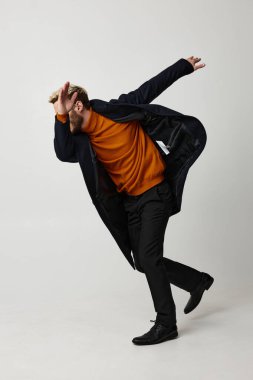 Siyah ceketli bir adam. El kol hareketleri yapıyor.