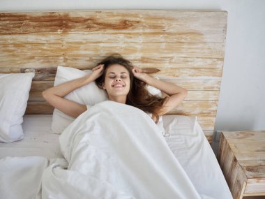 Sabah yatağında gözleri kapalı neşeli bir kadın.